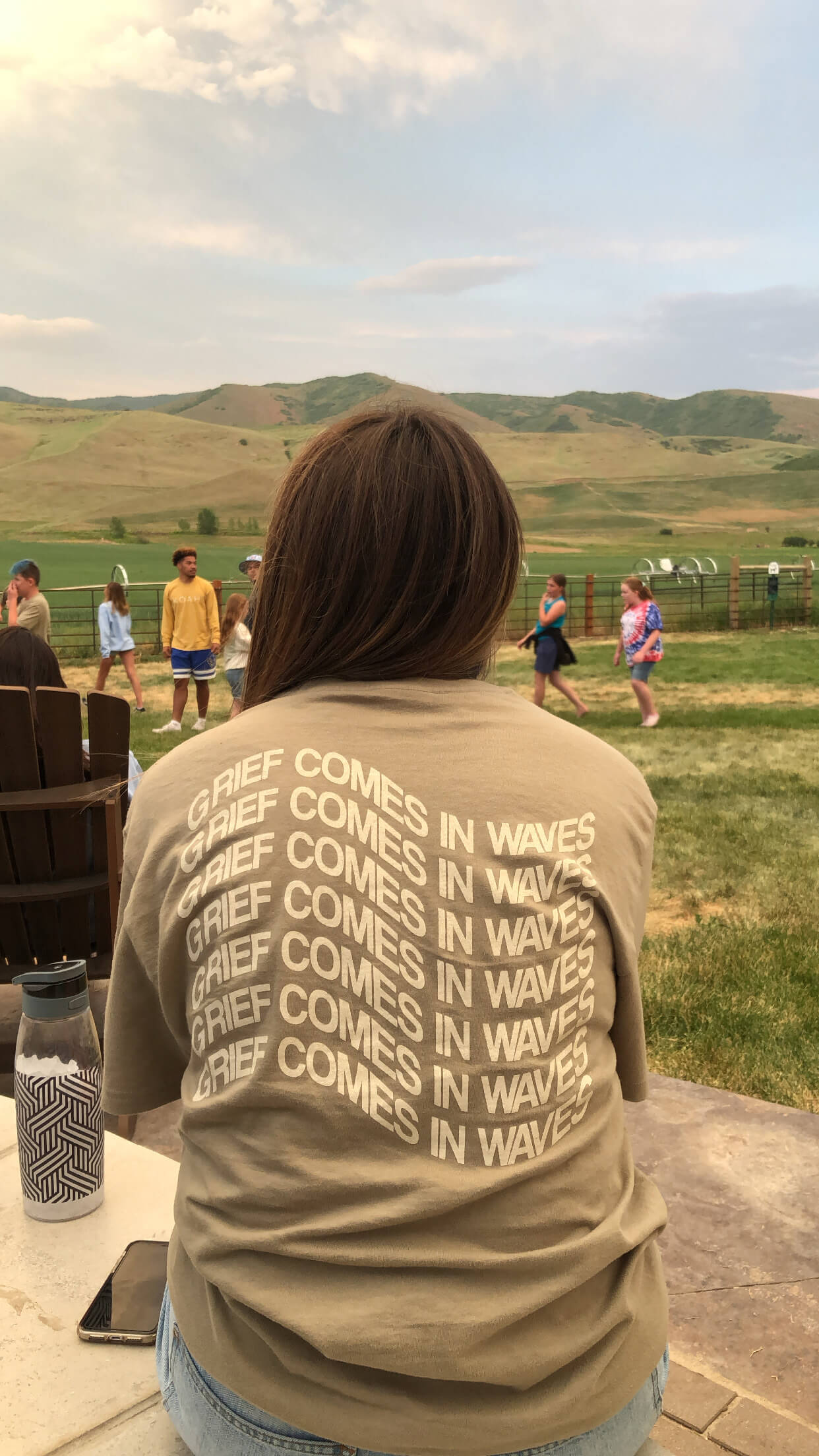 Camper wearing a tan shirt that says "Grief Comes In Waves".